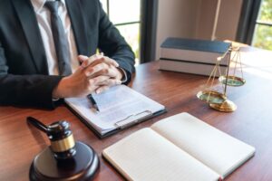 Lawyer sitting at a desk with legal documents, scales of justice, and a gavel nearby.