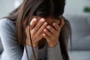 Woman with hands covering her face, expressing deep grief and emotional distress.