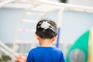 A child with a bandaged head injury stands on a playground; a child injury attorney can help.