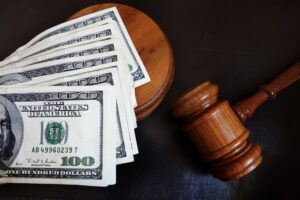 A gavel next to a stack of hundred-dollar bills, symbolizing legal compensation and justice.