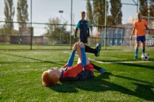 A child injured on a soccer field holds his knee in pain; a child injury attorney can assist.