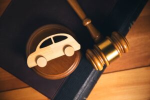 Gavel and wooden car figure on a book, symbolizing the need for legal advice after an accident.