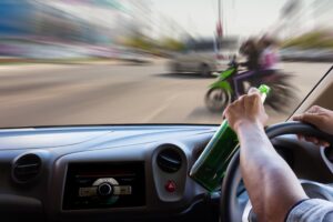 A drunk car driver about to hit a motorcycle on the road