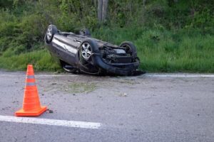 An overturned car lying on its roof on the street after a collision, with debris scattered around, illustrating the aftermath of a serious car accident.